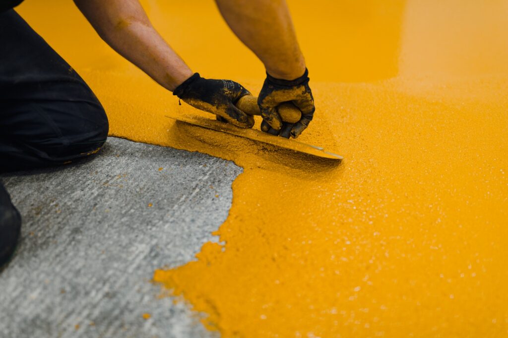 Professional construction worker applying floor paint or a new layer for a epoxy cast coating floor